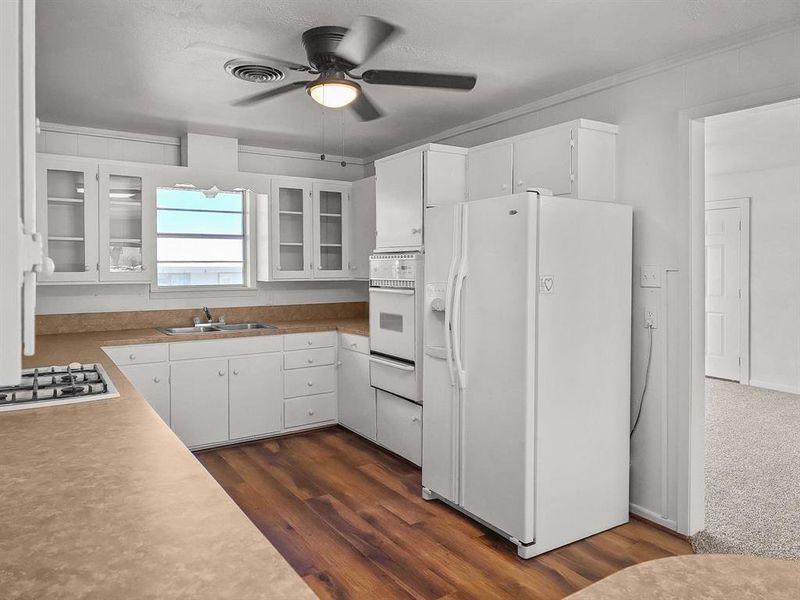 Kitchen featuring glass front cabinets, wall oven, a ceiling fan, and white appliances Kitchen featuring glass front cabinets, wall oven, a ceiling fan, and white appliances