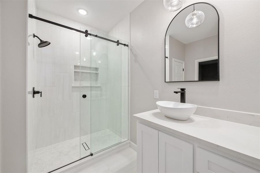 Bathroom featuring a shower with door and vanity