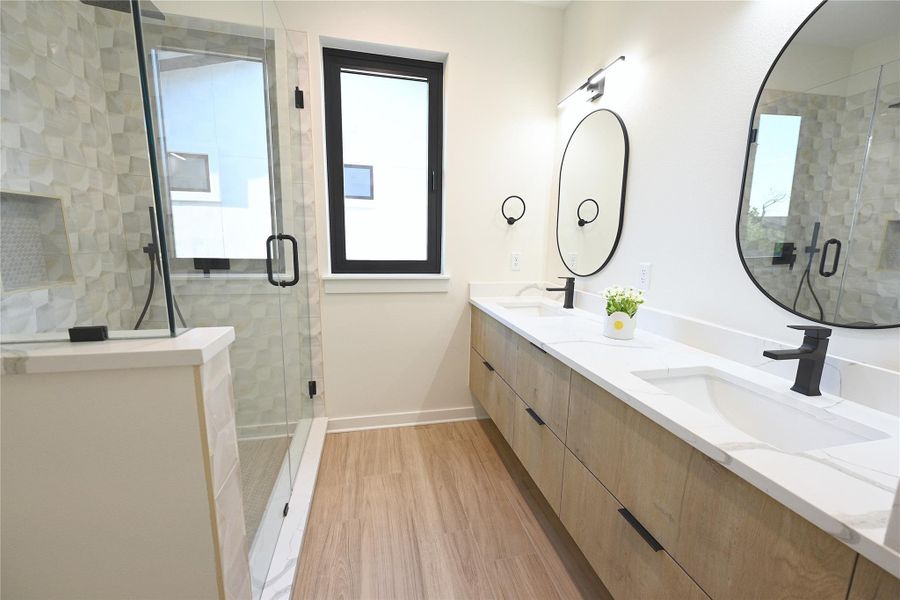 Master Bathroom featuring a double vanity with white countertops, modern black faucets, and two unique mirrors