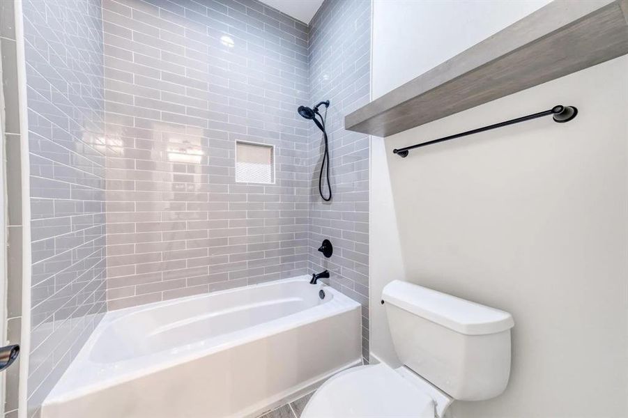 Bathroom with tiled shower / bath and toilet