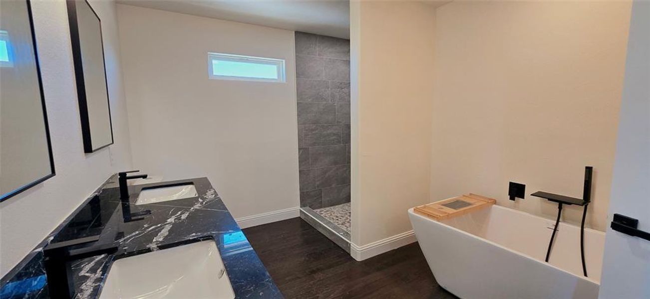 Bathroom featuring double vanity, a freestanding bath, walk in shower, and dark wood finished floors Bathroom featuring double vanity, a freestanding bath, walk in shower, and dark wood finished floors