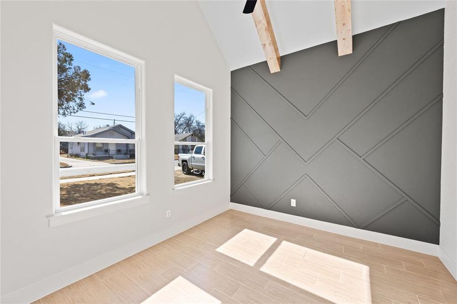 Empty room featuring a decorative wall, wood finish floors, lofted ceiling, and ceiling fan Empty room featuring a decorative wall, wood finish floors, lofted ceiling, and ceiling fan