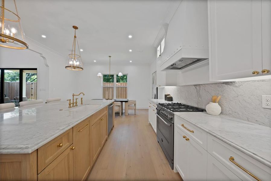 Expansive kitchen featuring a large central island with seating, a professional-grade range, full-height backsplash, recessed lighting, and dual pendant light fixtures