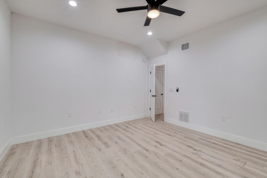 A well-lit bedroom with modern flooring and a ceiling fan. A well-lit bedroom with modern flooring and a ceiling fan.