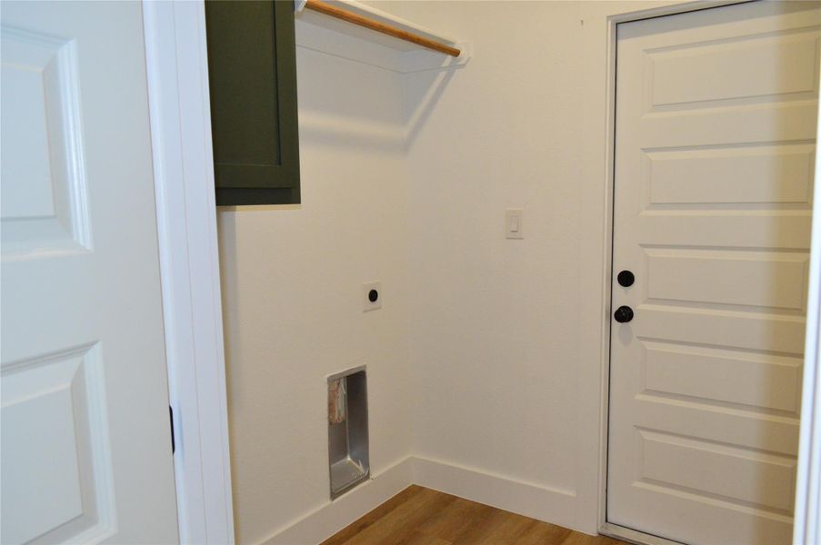 Washroom featuring light wood finished floors, electric dryer hookup, and cabinet space Washroom featuring light wood finished floors, electric dryer hookup, and cabinet space