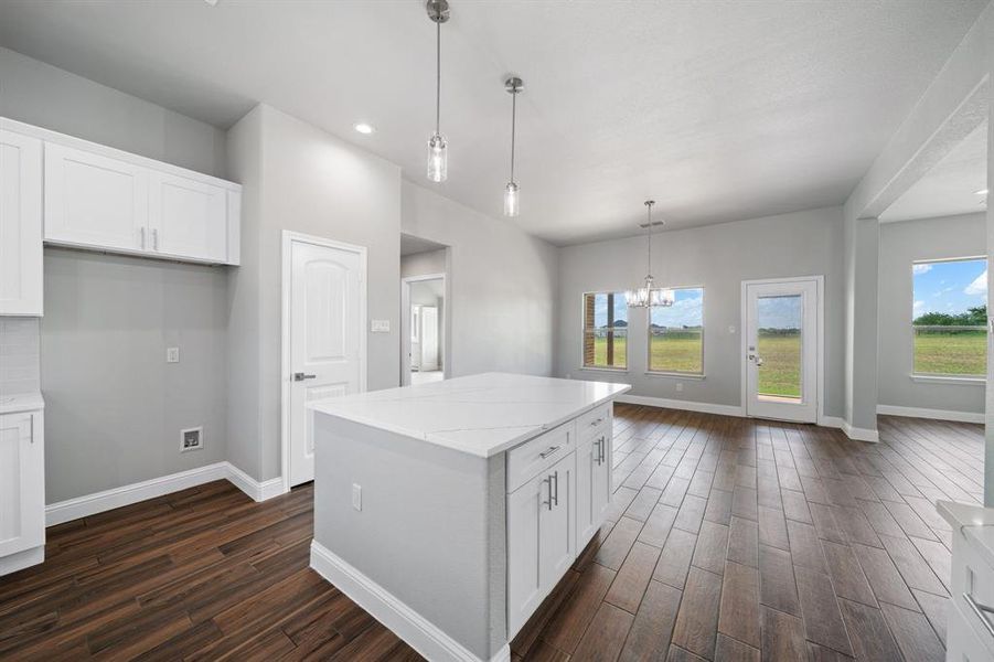 Kitchen with white cabinets, dark hardwood / wood-style flooring, and a kitchen island