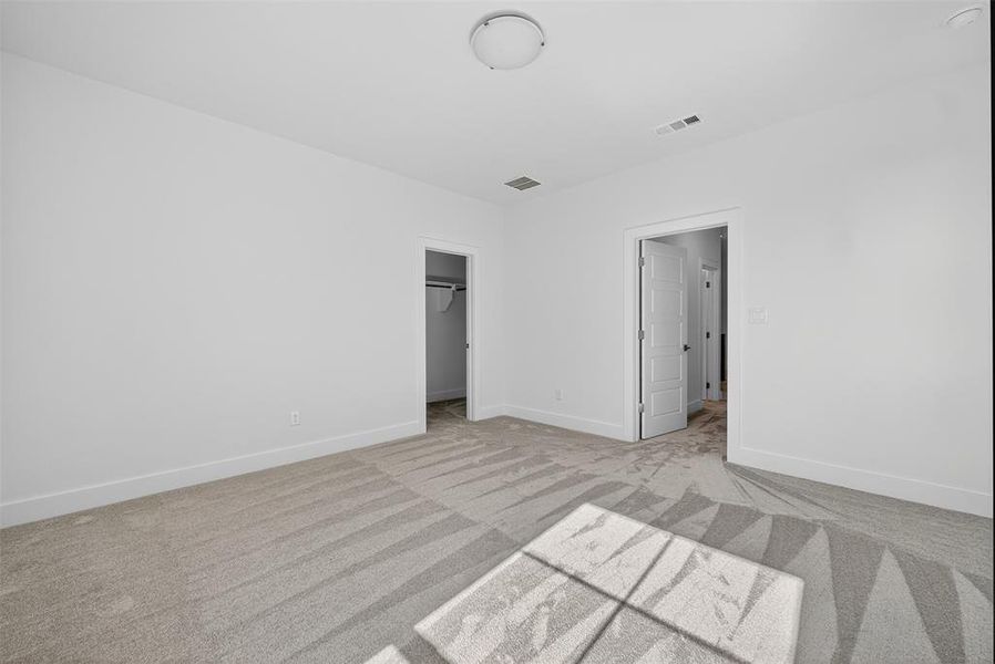 Unfurnished bedroom featuring a spacious closet and light carpet Unfurnished bedroom featuring a spacious closet and light carpet