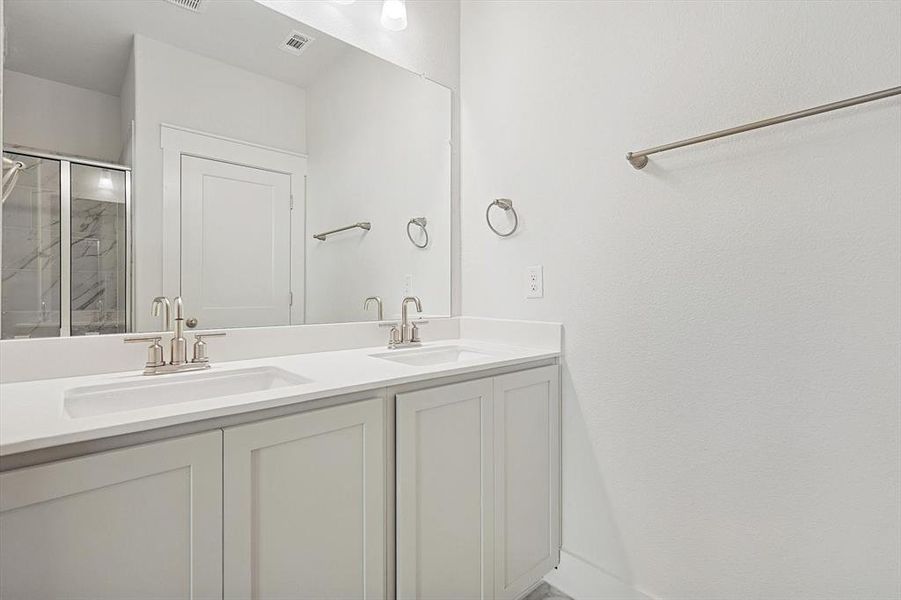 Full bathroom with a sink, visible vents, a shower stall, and double vanity