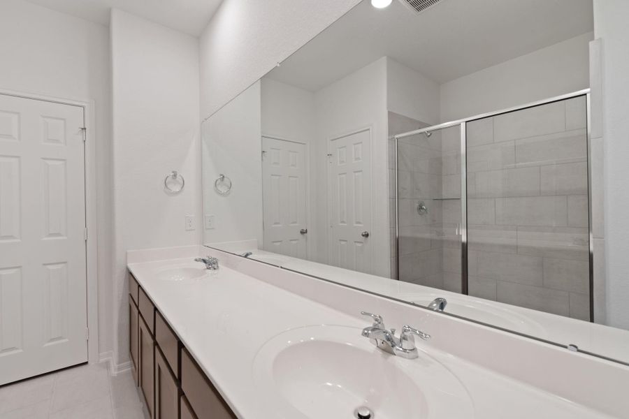 The en-suite bathroom offers a spa-like atmosphere with its elegant design, high end finishes, and tasteful lighting, creating a retreat within your own home.