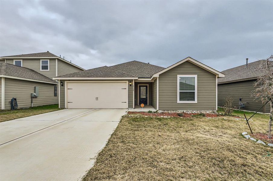 View of front facade featuring a front yard and a garage