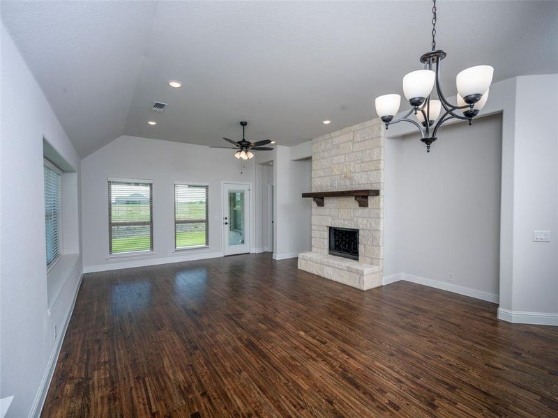 Unfurnished living room featuring a ceiling fan, dark wood finished floors, a fireplace, a chandelier, and vaulted ceiling Unfurnished living room featuring a ceiling fan, dark wood finished floors, a fireplace, a chandelier, and vaulted ceiling