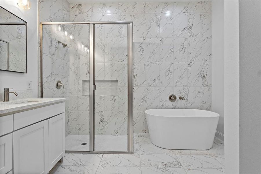 Bathroom featuring marble finish flooring, vanity, a freestanding tub, a marble finish shower, and tile walls Bathroom featuring marble finish flooring, vanity, a freestanding tub, a marble finish shower, and tile walls