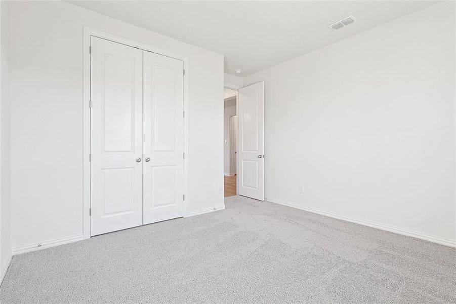 Unfurnished bedroom featuring light carpet and a closet