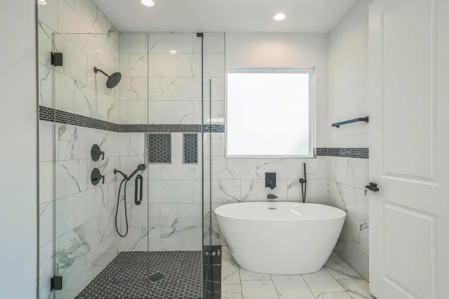 Bathroom with a freestanding tub, a shower stall, marble finish floors, tile walls, and recessed lighting