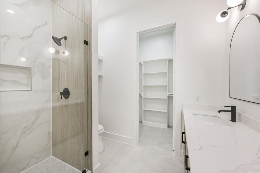 The primary bathroom features a glass panel shower, double sinks, and a walk in closet.