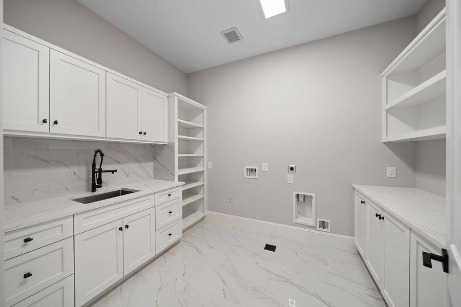 Utility room with built-in cabinetry, quartz folding counter, and open shelving for organized storage and hanging space.