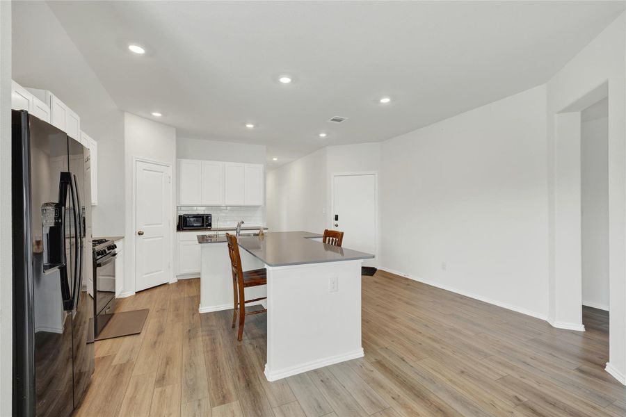 A well-appointed kitchen features stainless steel appliances, a center island with seating, and durable wood flooring.