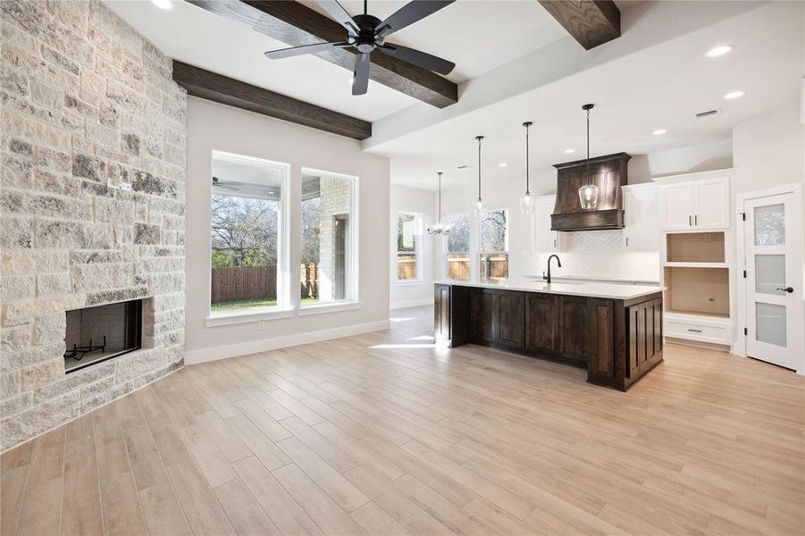 Kitchen featuring premium range hood, dark brown cabinetry, a kitchen island with sink, pendant lighting, and beamed ceiling