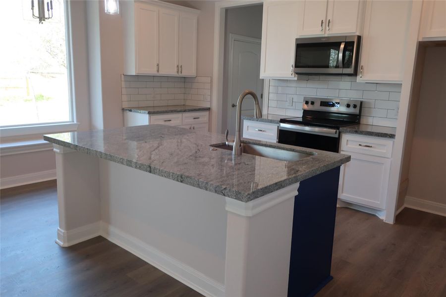Kitchen featuring white cabinets, appliances with stainless steel finishes, dark wood-type flooring, and a sink Kitchen featuring white cabinets, appliances with stainless steel finishes, dark wood-type flooring, and a sink