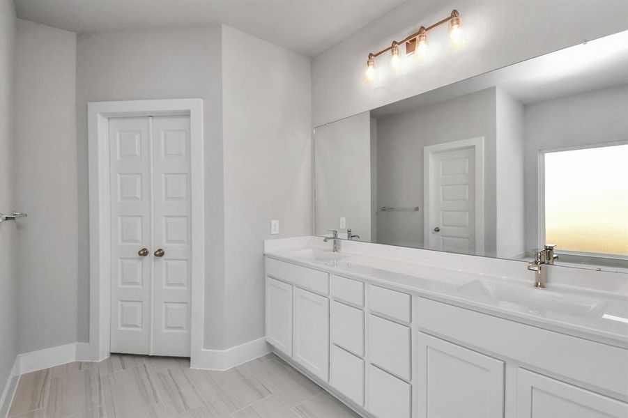 Sophisticated vanity, featuring double sinks, light-colored countertops, contemporary hardware, and exquisite vanity lights.