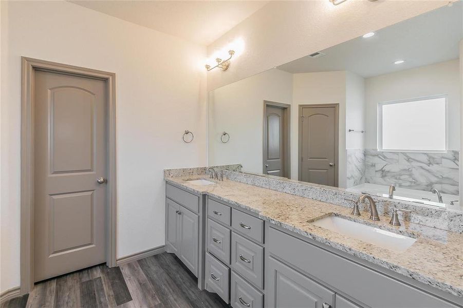 Bathroom featuring a garden tub, double vanity, dark wood finished floors, and recessed lighting