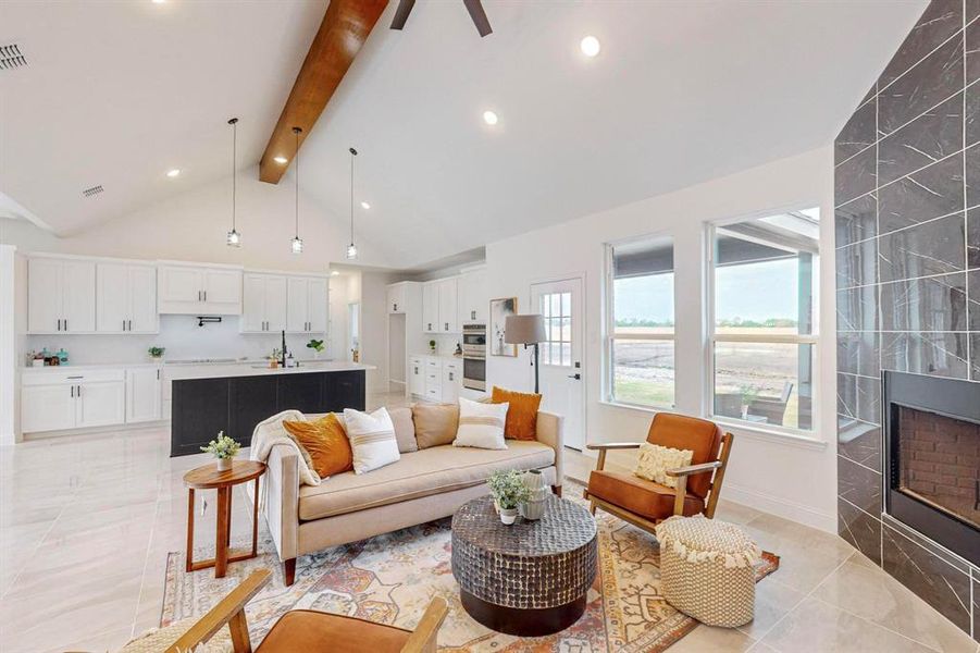 Tiled living room with sink, high vaulted ceiling, ceiling fan, beam ceiling, and a fireplace