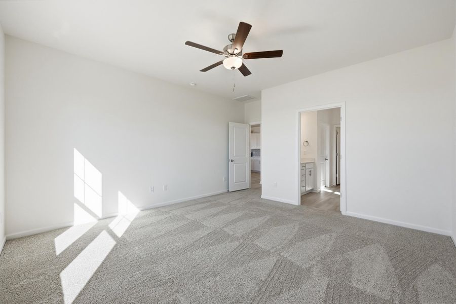 Unfurnished bedroom featuring a ceiling fan, light colored carpet, and ensuite bathroom