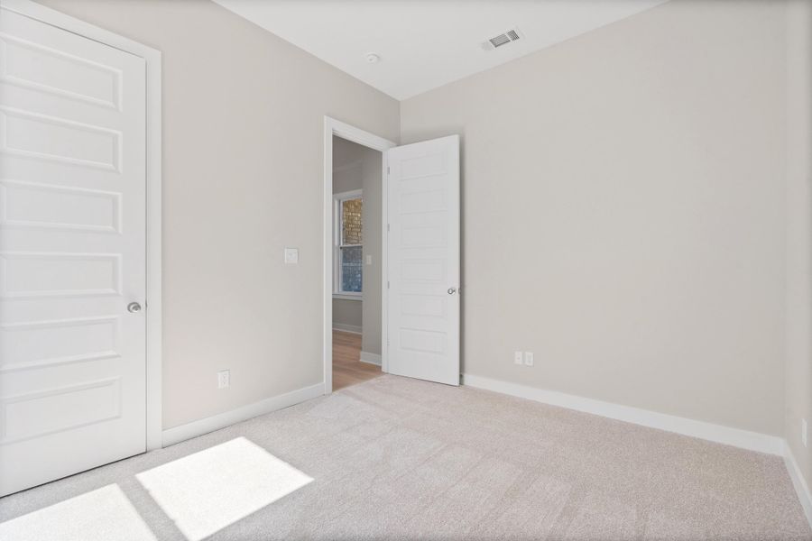 Unfurnished bedroom with light carpet and baseboards
