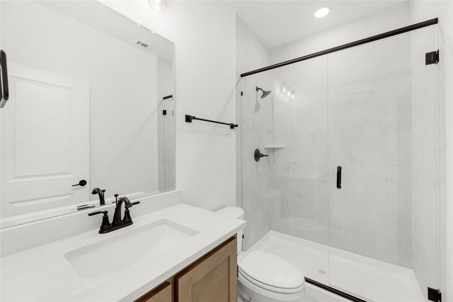 Bathroom with white tile walk-in shower, glass door, single vanity, and black hardware accents