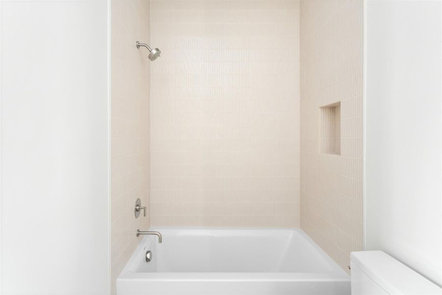 Another ensuite secondary bath with tub/shower combo and soft, textural tile surround.