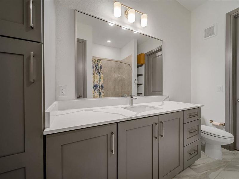 Bathroom featuring vanity, tiled shower, and light marble finish flooring
