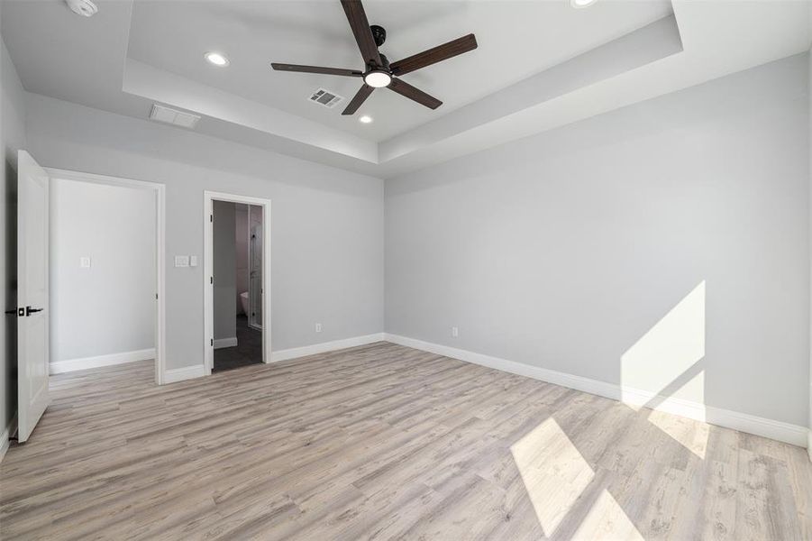Unfurnished room with a tray ceiling, a ceiling fan, light wood-style floors, recessed lighting, and a smoke detector Unfurnished room with a tray ceiling, a ceiling fan, light wood-style floors, recessed lighting, and a smoke detector
