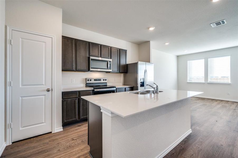 Kitchen featuring appliances with stainless steel finishes, dark hardwood / wood-style flooring, a kitchen island with sink, and sink