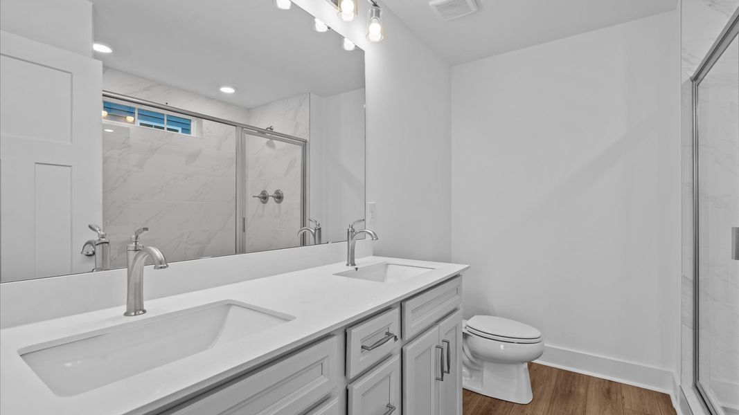 Highly functional and elegant en-suite with dual vanities, tiled walk-in shower, and refined finishes