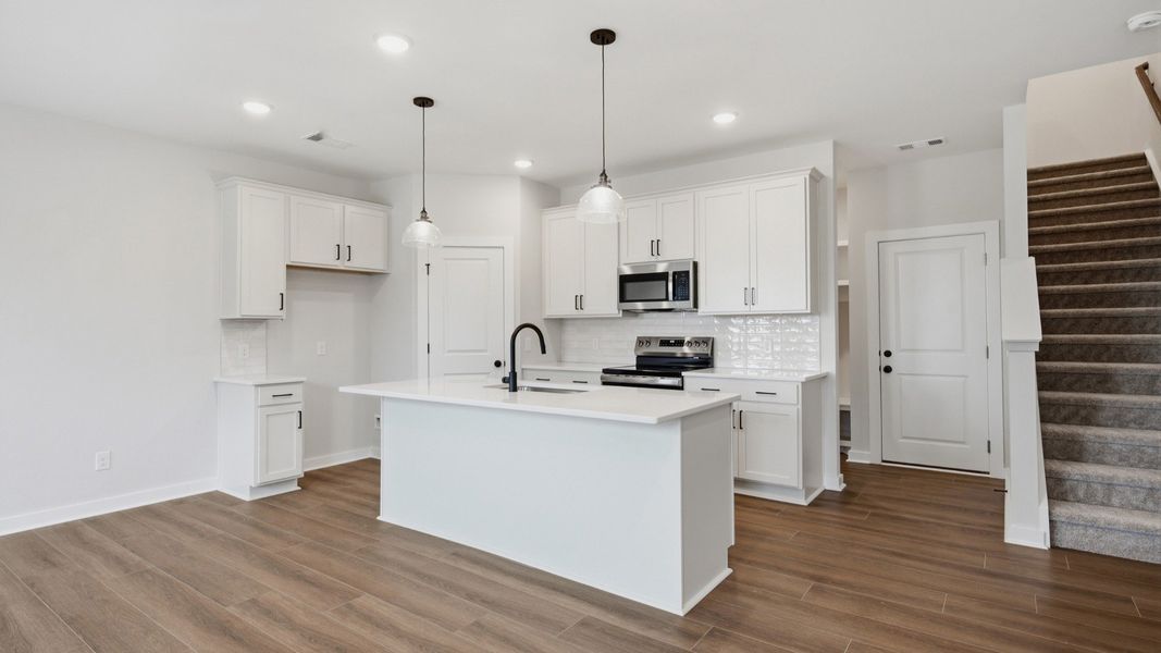Kitchen with island and pantry door next to entryway and stairs