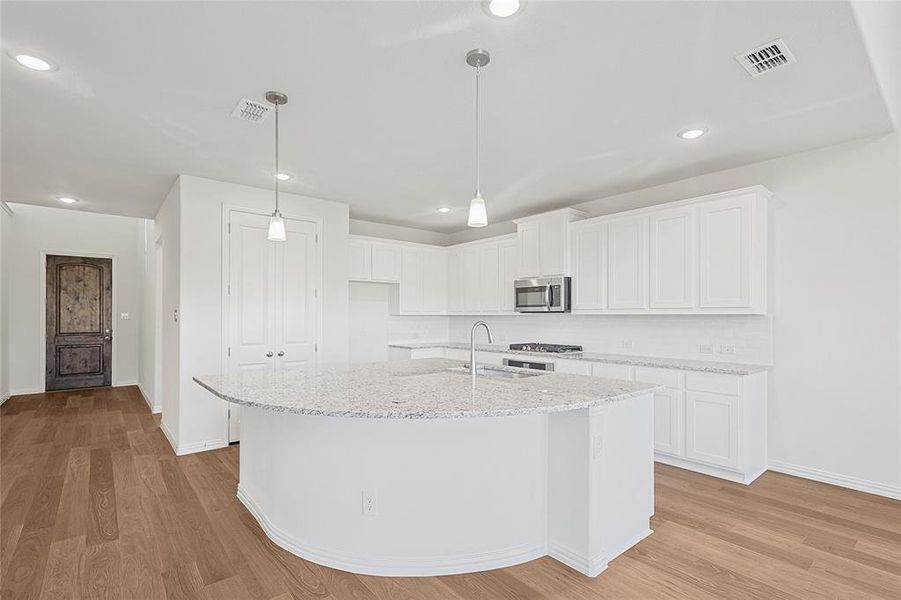 Kitchen with white cabinetry, sink, and light wood-type flooring