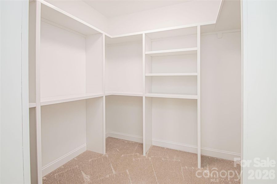 The spacious primary closet is outfitted with custom solid wood shelving for organized and stylish storage.