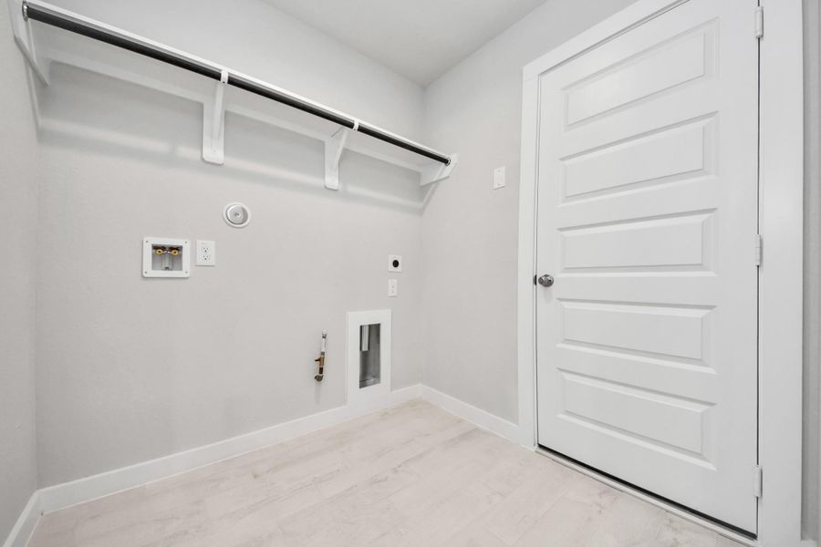 A perfect blend of functionality and comfort. Capture the essence of easy living with a first-floor laundry room, thoughtfully equipped with shelving for effortless organization. Both electric and gas connections available. Sample photo of completed home with similar floor plan. Actual colors and selections may vary.