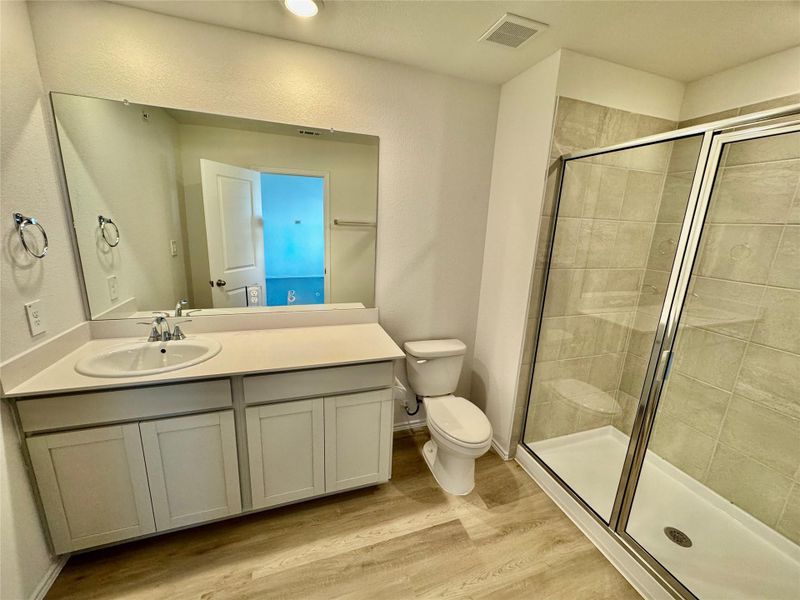 Bathroom featuring vanity, a stall shower, and light wood finished floors