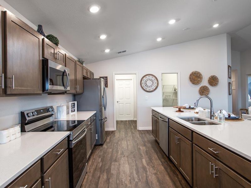 Open kitchen with counter-height island and walk-in pantry - Serendipity home plan by Highland Homes