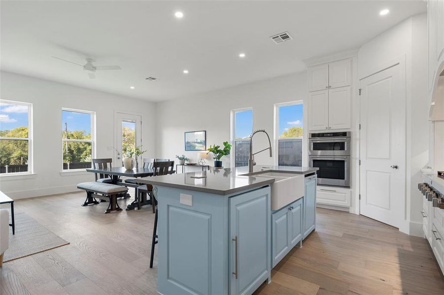 Kitchen featuring recessed lighting, an island with sink, white cabinetry, light wood finished floors, and blue cabinets Kitchen featuring recessed lighting, an island with sink, white cabinetry, light wood finished floors, and blue cabinets