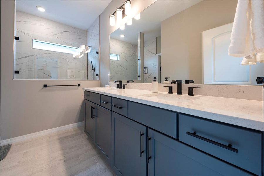 primary bathroom with quartz countertops, doubl sinks, walk-in shower