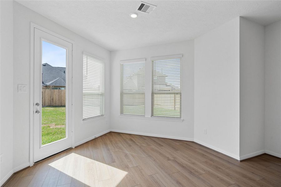 Start your day with a warm cup of coffee and quality time in this charming breakfast nook! Highlights include large windows with blinds, custom neutral paint, vinyl plank flooring, recessed lighting, high ceilings, and a convenient door leading to the spacious backyard.