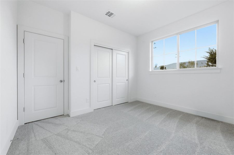 Unfurnished bedroom featuring light carpet and a closet