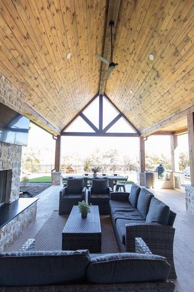 View of patio featuring an outdoor stone fireplace and an outdoor kitchen with living area