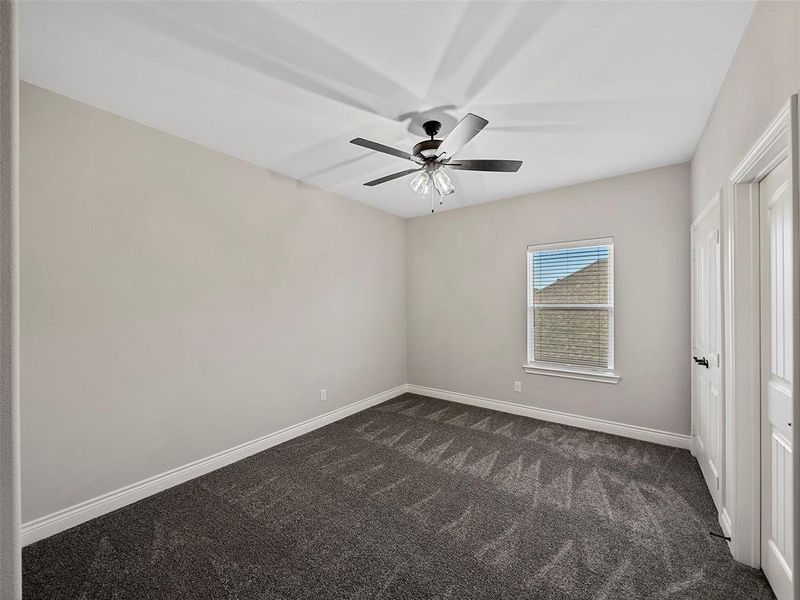 Unfurnished bedroom featuring dark colored carpet and a ceiling fan Unfurnished bedroom featuring dark colored carpet and a ceiling fan