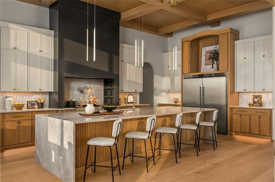 Gourmet kitchen featuring a substantial island with stone surfacing, a coffered wood-finish ceiling, integrated stainless steel appliances, a paneled range hood, and mixed-material cabinetry