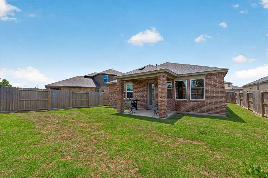 Charming brick home with a spacious backyard, featuring a covered patio perfect for outdoor relaxation and entertaining.
