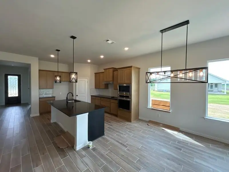 Open-concept kitchen and dining area featuring wood-finish tile flooring