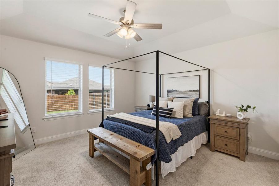 Carpeted room with a vaulted ceiling, dual windows, and ceiling fan with light fixture